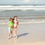 a couple of kids that are standing in the sand